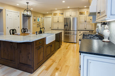 Light wood floor kitchen photo in Other with a farmhouse sink, beaded inset cabinets, granite countertops, white backsplash and stainless steel appliances