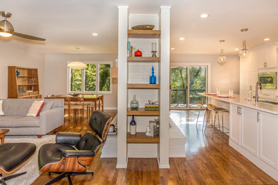 Example of a mid-sized 1950s l-shaped medium tone wood floor and brown floor open concept kitchen design in Other with an undermount sink, shaker cabinets, white cabinets, quartzite countertops, white backsplash, subway tile backsplash, stainless steel appliances and an island