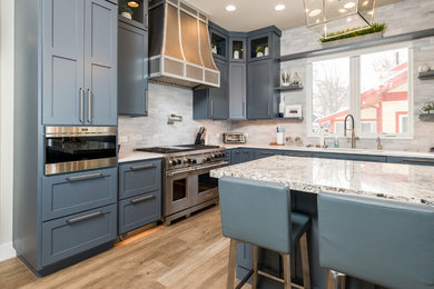 Example of a large transitional l-shaped medium tone wood floor and brown floor eat-in kitchen design in Other with an undermount sink, flat-panel cabinets, quartz countertops, stainless steel appliances, an island, blue cabinets, gray backsplash and white countertops