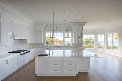 Classic kitchen in New York with white cabinets, marble worktops, white splashback, medium hardwood flooring and white worktops.