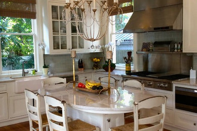 Идея дизайна: угловая кухня-гостиная в стиле неоклассика (современная классика) с фасадами с утопленной филенкой, белыми фасадами, столешницей из кварцита, фартуком из стеклянной плитки и островом