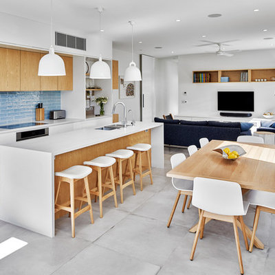 Trendy galley gray floor open concept kitchen photo in Sydney with an undermount sink, flat-panel cabinets, white cabinets, blue backsplash, stainless steel appliances, an island and white countertops