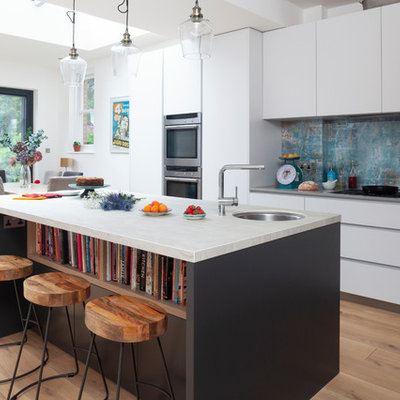 Mid-sized trendy medium tone wood floor and brown floor eat-in kitchen photo in London with an undermount sink, flat-panel cabinets, white cabinets, blue backsplash, an island, gray countertops, marble countertops, metal backsplash and stainless steel appliances