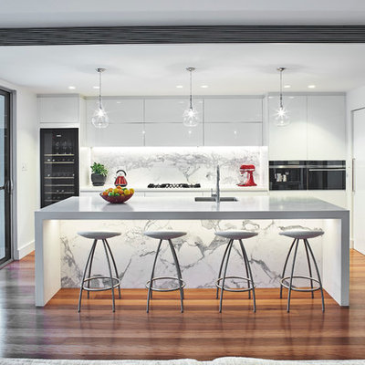 Trendy l-shaped medium tone wood floor open concept kitchen photo in Sydney with an undermount sink, flat-panel cabinets, white cabinets, stainless steel appliances, an island and marble backsplash