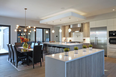 Eat-in kitchen - large modern l-shaped medium tone wood floor and brown floor eat-in kitchen idea in Calgary with an undermount sink, flat-panel cabinets, medium tone wood cabinets, quartz countertops, white backsplash, stone slab backsplash, stainless steel appliances and an island