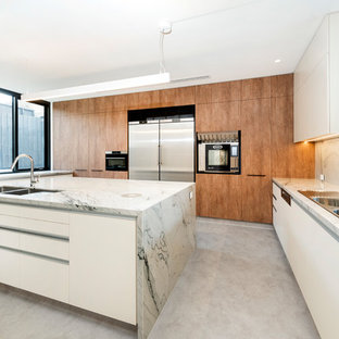 This is an example of a modern u-shaped kitchen in Melbourne with a drop-in sink, flat-panel cabinets, medium wood cabinets, stainless steel appliances, with island, grey floor and grey benchtop.