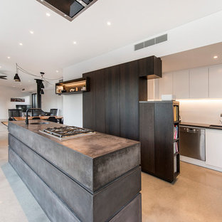 Contemporary u-shaped open plan kitchen in Perth with dark wood cabinets, concrete benchtops, white splashback, porcelain splashback, concrete floors, with island, grey floor, an undermount sink, flat-panel cabinets and stainless steel appliances.