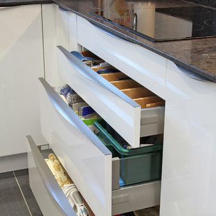 Diseño de cocina en U, contemporánea, pequeña, cerrada, con fregadero encastrado, armarios con paneles lisos, puertas de armario blancas, encimera de cuarzo compacto, salpicadero negro, electrodomésticos de acero inoxidable, suelo de baldosas de porcelana y península