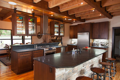 Photo of a large rustic u-shaped open plan kitchen in St Louis with a submerged sink, shaker cabinets, dark wood cabinets, granite worktops, stainless steel appliances, medium hardwood flooring, multiple islands, stone tiled splashback and brown floors.
