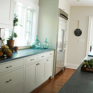 Transitional l-shaped kitchen photo in New York with a farmhouse sink, shaker cabinets, gray cabinets, limestone countertops, gray backsplash, subway tile backsplash and stainless steel appliances