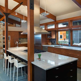 Foto de cocina moderna, grande, con fregadero bajoencimera, armarios con paneles lisos, puertas de armario de madera oscura, encimera de granito, salpicadero verde, salpicadero con mosaicos de azulejos, electrodomésticos de acero inoxidable, suelo de pizarra y una isla