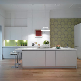 Design ideas for a large contemporary open plan kitchen in London with an undermount sink, flat-panel cabinets, white cabinets, solid surface benchtops, glass sheet splashback and with island.