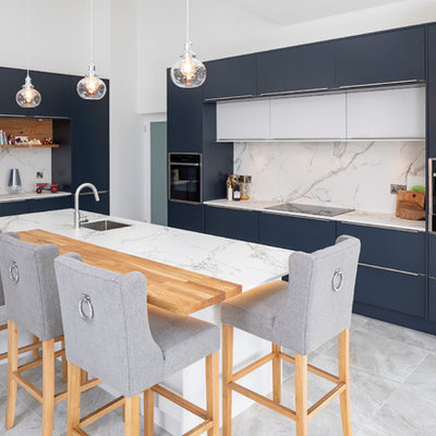 Mid-sized trendy galley gray floor kitchen photo in Other with an undermount sink, flat-panel cabinets, blue cabinets, gray backsplash, black appliances, an island and gray countertops