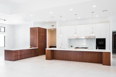Photo of an expansive contemporary open plan kitchen in Phoenix with a submerged sink, flat-panel cabinets, white cabinets, engineered stone countertops, glass sheet splashback and an island.
