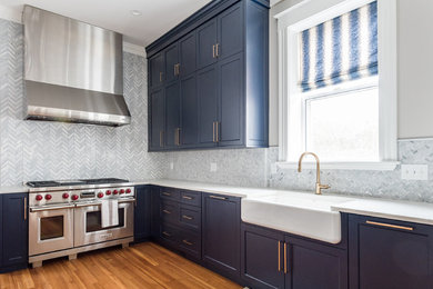 Example of a large transitional u-shaped medium tone wood floor and brown floor eat-in kitchen design in Richmond with a farmhouse sink, shaker cabinets, blue cabinets, quartz countertops, gray backsplash, marble backsplash, stainless steel appliances, a peninsula and white countertops