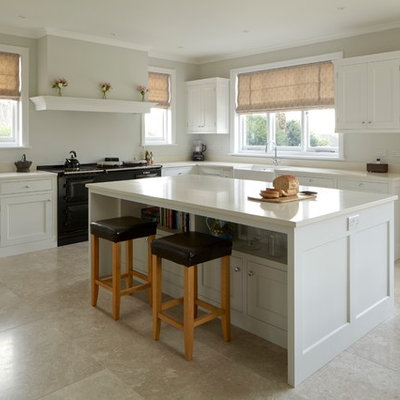 Mid-sized elegant l-shaped limestone floor and beige floor kitchen photo in Hampshire with a farmhouse sink, shaker cabinets, white cabinets, quartzite countertops, black appliances, an island and white countertops