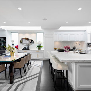 This is an example of a contemporary l-shaped eat-in kitchen in Sydney with a double-bowl sink, recessed-panel cabinets, white cabinets, white splashback, stone slab splashback, dark hardwood floors, with island and white benchtop.