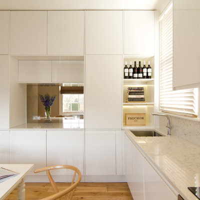 Eat-in kitchen - mid-sized contemporary l-shaped medium tone wood floor eat-in kitchen idea in London with a single-bowl sink, flat-panel cabinets, white cabinets, quartz countertops, stainless steel appliances and no island