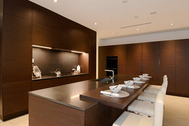 Example of a transitional l-shaped kitchen design in Chicago with flat-panel cabinets, dark wood cabinets, black backsplash, paneled appliances, an island and black countertops