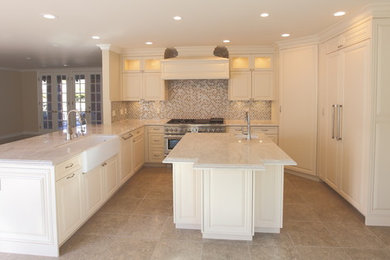 This is an example of a medium sized traditional u-shaped kitchen/diner in Los Angeles with a belfast sink, raised-panel cabinets, beige cabinets, limestone worktops, beige splashback, glass tiled splashback, coloured appliances, slate flooring and an island.