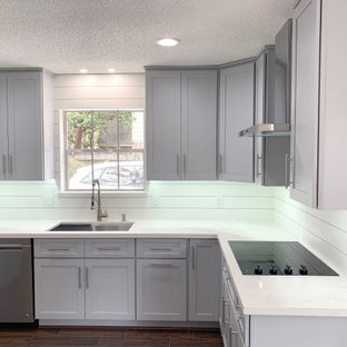 This is an example of a mid-sized transitional kitchen in Houston with a single-bowl sink, shaker cabinets, grey cabinets, quartzite benchtops, white splashback, shiplap splashback, stainless steel appliances, laminate floors, brown floor and white benchtop.
