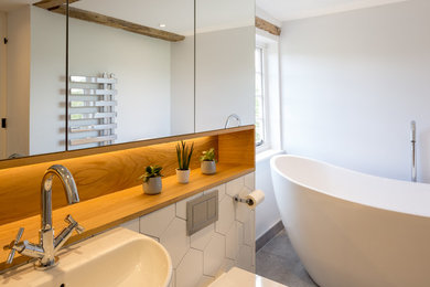 Modelo de cuarto de baño actual con puertas de armario de madera oscura, suelo de cemento y suelo gris