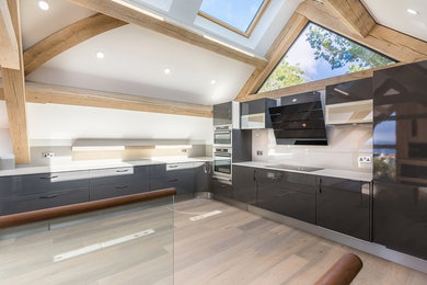 Design ideas for a large contemporary u-shaped open plan kitchen in Channel Islands with an integrated sink, flat-panel cabinets, black cabinets, granite worktops, white splashback, integrated appliances, no island and white worktops.