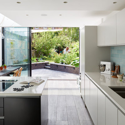 Inspiration for a contemporary eat-in kitchen remodel in London with a double-bowl sink, flat-panel cabinets, white cabinets, blue backsplash, subway tile backsplash and an island