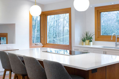 Inspiration for a mid-sized transitional medium tone wood floor kitchen remodel in Vancouver with shaker cabinets, white cabinets, quartz countertops, white backsplash, porcelain backsplash, stainless steel appliances, an island and white countertops
