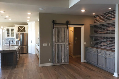 Große Urige Wohnküche mit Granit-Arbeitsplatte, Küchengeräten aus Edelstahl, hellem Holzboden und Kücheninsel in Omaha