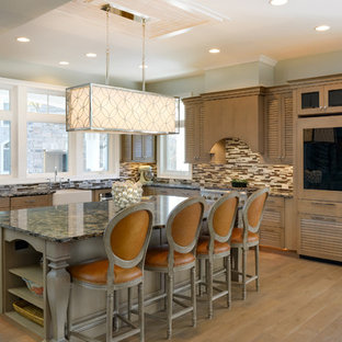 This is an example of a large country l-shaped open plan kitchen in Other with a farmhouse sink, louvered cabinets, medium wood cabinets, quartz benchtops, multi-coloured splashback, glass tile splashback, panelled appliances, medium hardwood floors and with island.