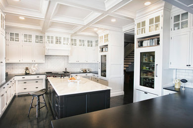 Inspiration for a large transitional u-shaped dark wood floor and black floor enclosed kitchen remodel in Other with a farmhouse sink, shaker cabinets, white cabinets, marble countertops, white backsplash, subway tile backsplash, paneled appliances and an island