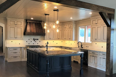 Photo of a large country u-shaped kitchen pantry in Other with a belfast sink, beaded cabinets, distressed cabinets, granite worktops, white splashback, porcelain splashback, stainless steel appliances, dark hardwood flooring, an island and brown floors.