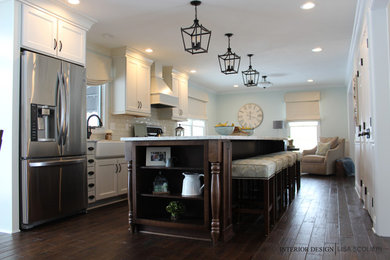 Example of a large country single-wall dark wood floor and brown floor eat-in kitchen design in Other with a farmhouse sink, recessed-panel cabinets, white cabinets, quartz countertops, white backsplash, subway tile backsplash, stainless steel appliances and an island