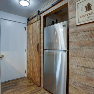 This is an example of a mid-sized country l-shaped open plan kitchen in Other with an undermount sink, glass-front cabinets, distressed cabinets, concrete benchtops, multi-coloured splashback, ceramic splashback, stainless steel appliances, laminate floors, with island, brown floor and black benchtop.