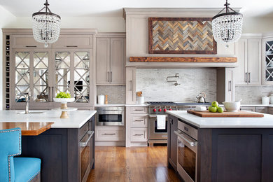 Transitional medium tone wood floor kitchen photo in Philadelphia with an undermount sink, shaker cabinets, beige cabinets, multicolored backsplash, stainless steel appliances, two islands, white countertops, marble countertops and mosaic tile backsplash