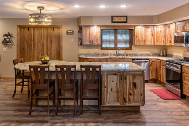 Example of a mid-sized mountain style l-shaped vinyl floor and brown floor eat-in kitchen design in St Louis with an undermount sink, recessed-panel cabinets, light wood cabinets, granite countertops, beige backsplash, marble backsplash, stainless steel appliances, an island and brown countertops