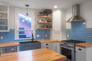 シアトルにある高級な中くらいなラスティックスタイルのおしゃれなキッチン (エプロンフロントシンク、シェーカースタイル扉のキャビネット、白いキャビネット、木材カウンター、青いキッチンパネル、セラミックタイルのキッチンパネル、シルバーの調理設備、濃色無垢フローリング、マルチカラーの床、マルチカラーのキッチンカウンター) の写真