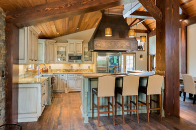 Bild på ett stort rustikt kök, med en rustik diskho, luckor med infälld panel, skåp i slitet trä, granitbänkskiva, stänkskydd i sten, rostfria vitvaror, mörkt trägolv och en köksö