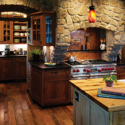 Mountain style dark wood floor kitchen photo in Denver with dark wood cabinets, brown backsplash, stainless steel appliances, a drop-in sink, recessed-panel cabinets, wood countertops, stone slab backsplash and an island