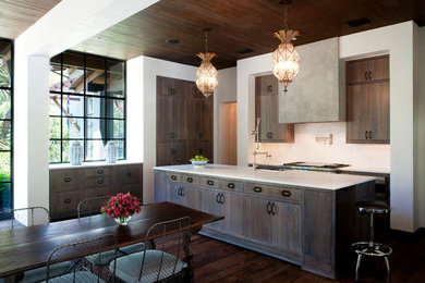 Inspiration for a medium sized traditional l-shaped kitchen/diner in Austin with a belfast sink, flat-panel cabinets, stainless steel appliances, dark hardwood flooring, an island, dark wood cabinets, engineered stone countertops and brown floors.
