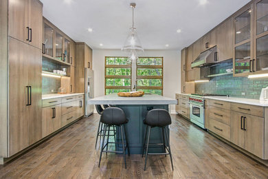 Design ideas for a rustic kitchen in Grand Rapids with a submerged sink, flat-panel cabinets, engineered stone countertops, green splashback, glass tiled splashback, stainless steel appliances and medium hardwood flooring.