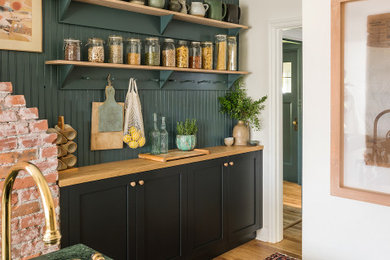Enclosed kitchen - mid-sized cottage galley light wood floor and brown floor enclosed kitchen idea in Vancouver with an undermount sink, shaker cabinets, black cabinets, granite countertops, green backsplash, shiplap backsplash, stainless steel appliances, an island and green countertops