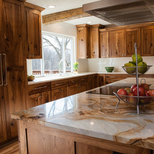 Réalisation d'une cuisine américaine chalet en L de taille moyenne avec des portes de placard en bois brun, un plan de travail en quartz, une crédence blanche, une crédence en carrelage métro, un électroménager encastrable, un sol en bois clair, un îlot central, un évier encastré, un placard à porte shaker et un plan de travail multicolore.