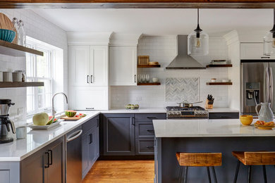 Inspiration for a transitional l-shaped medium tone wood floor kitchen remodel in Chicago with an undermount sink, shaker cabinets, blue cabinets, white backsplash, subway tile backsplash, stainless steel appliances, an island and white countertops
