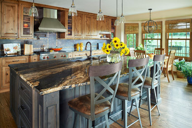 Inspiration for a large rustic l-shaped medium tone wood floor open concept kitchen remodel in Denver with light wood cabinets, granite countertops, a double-bowl sink, raised-panel cabinets, brown backsplash, porcelain backsplash, stainless steel appliances and an island