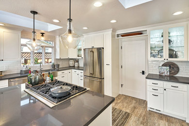 Open concept kitchen - large rustic u-shaped porcelain tile and gray floor open concept kitchen idea in San Francisco with a farmhouse sink, raised-panel cabinets, white cabinets, soapstone countertops, white backsplash, subway tile backsplash, stainless steel appliances and an island