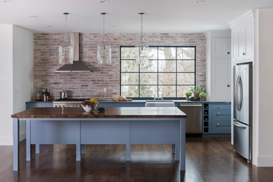 Open concept kitchen - mid-sized farmhouse l-shaped dark wood floor open concept kitchen idea in Boston with a farmhouse sink, recessed-panel cabinets, blue cabinets, wood countertops, brick backsplash, stainless steel appliances and an island