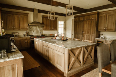 Example of a large mountain style u-shaped exposed beam open concept kitchen design in Chicago with paneled appliances and an island