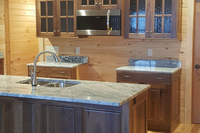 Inspiration for a rustic eat-in kitchen remodel in New York with a double-bowl sink, raised-panel cabinets, dark wood cabinets, granite countertops and an island